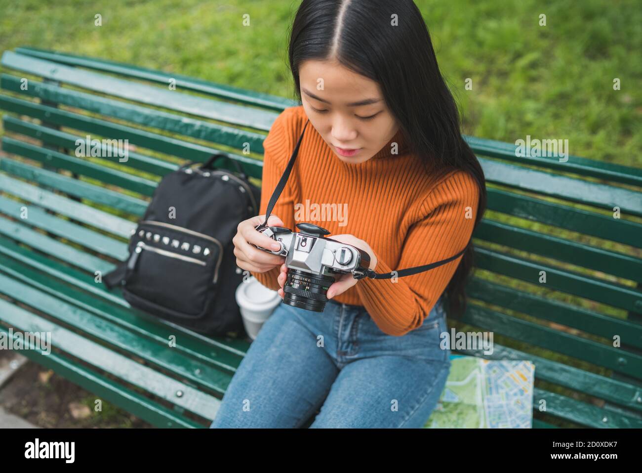 Portrait of young Asian woman using a professional digital camera in the park outdoors. Photography concept. Stock Photo