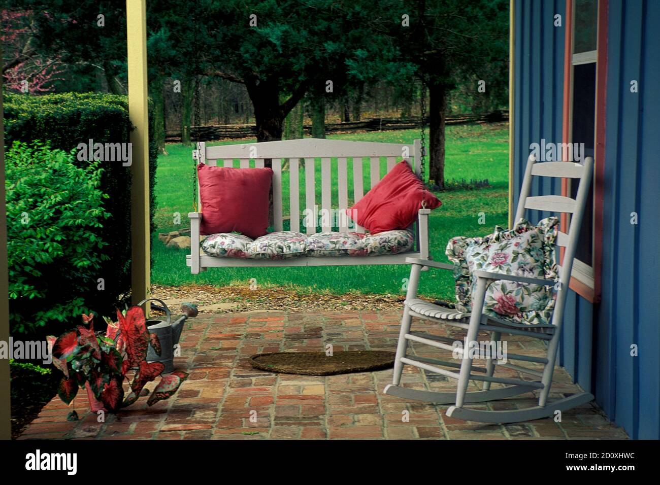 Intimate front porch and entryway into house with swing glider, rocker, and colorful pillows Stock Photo