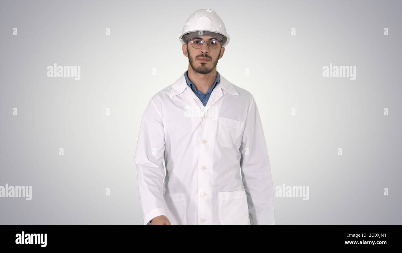 Young engineer in robe and helmet putting glasses on while walki Stock Photo