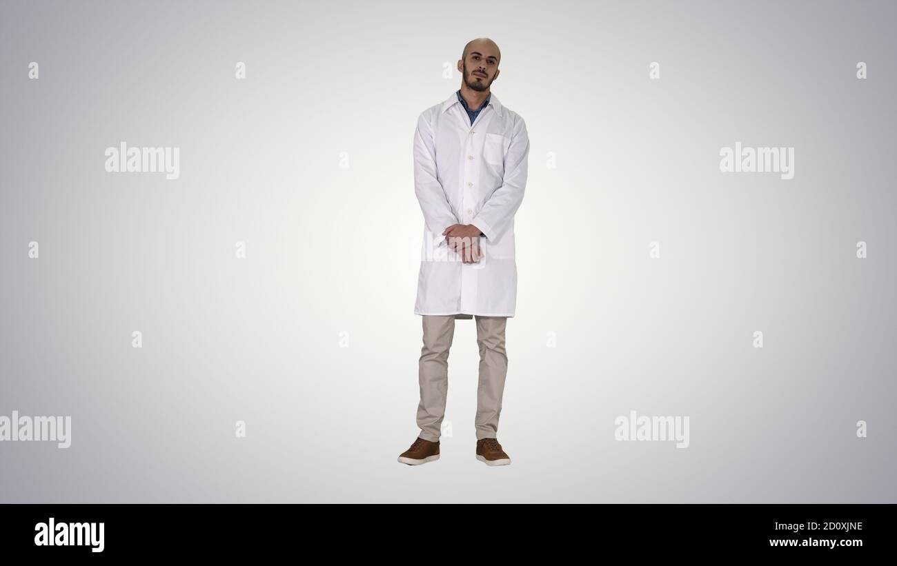 Standing young serious arab doctor on gradient background. Stock Photo