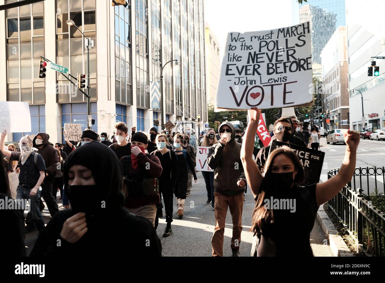Atlanta, Georgia, USA. October 3, 2020: A demonstrator participatimg in a march against police brutality in Atlanta, holds a sign saying We must MARCH to the POLLS like NEVER EVER BEFORE - John Lewis VOTE. Credit: John Arthur Brown/ZUMA Wire/Alamy Live News Stock Photo