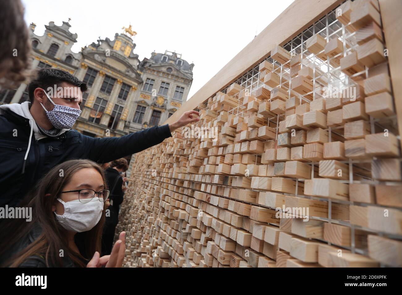 Brussels, Belgium. 3rd Oct, 2020. People take the wooden blocks from 'the Disappearing Wall' at the Grand Place, Brussels, Belgium, Oct. 3, 2020. The art installation 'the Disappearing Wall' was set up to mark the 30th anniversary of the German reunification. It consists of 6,000 wooden blocks with quotes of worldwide artists and thinkers. After passers-by take away the wooden blocks with quotes, the installation will be left with an translucent frame, showing the concept 'the wall will disappear'. Credit: Zheng Huansong/Xinhua/Alamy Live News Stock Photo