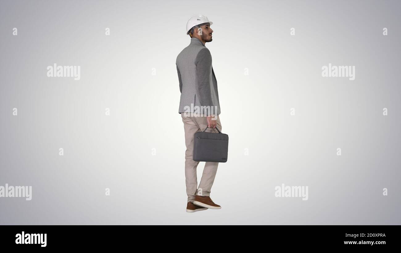 Engineer in helmet with briefcase walking on gradient background Stock Photo