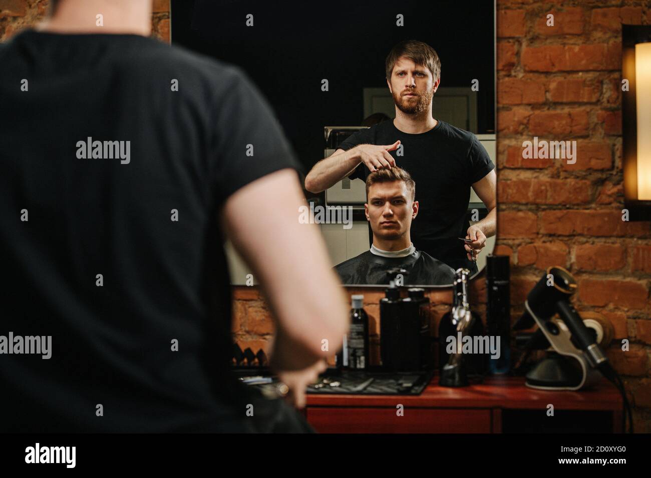 Male hairdresser asking a client in a chair about haircut final