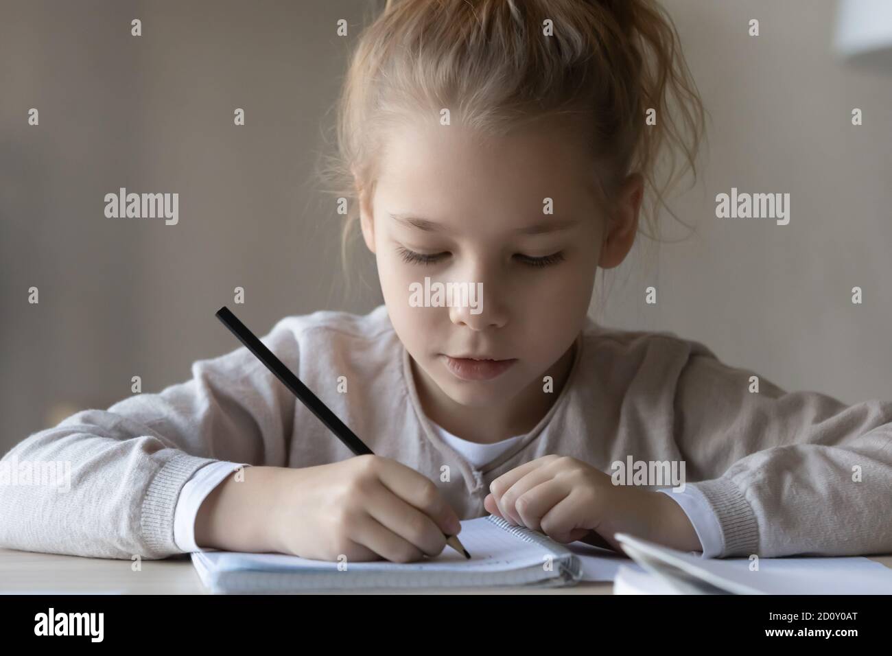 Close up busy focused little girl studying, writing in notebook Stock Photo
