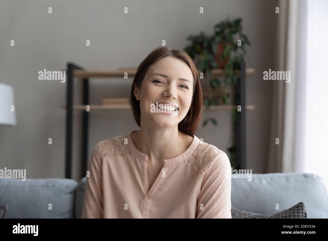 Head shot portrait smiling young woman sitting on couch Stock Photo - Alamy