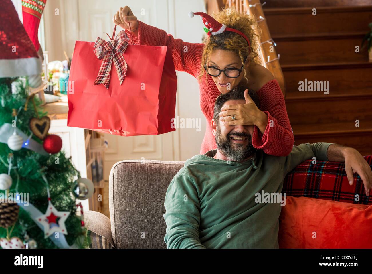 Christmas time and holiday season concept with happy people couple at home in surprise and gift presents exchange - happiness and joyful with woman an Stock Photo
