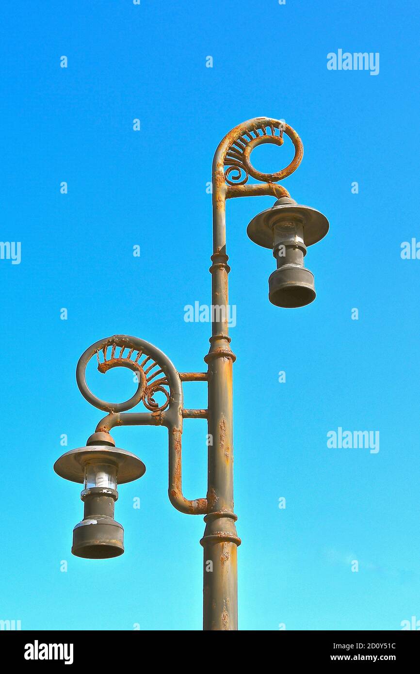 Ornate metal lamp posts corroded with rust, against the backdrop of an