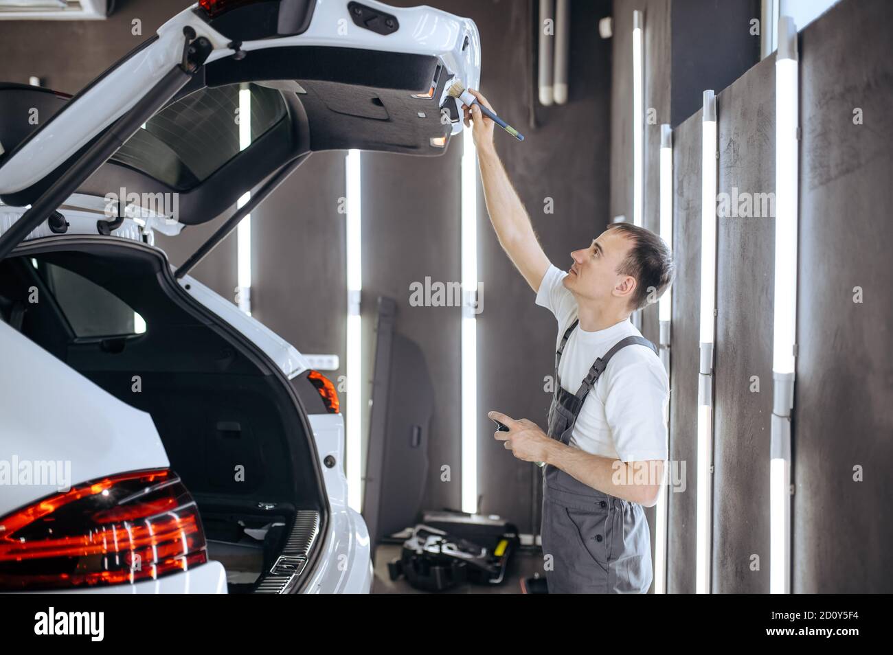 Worker with brush wipes car trunk door, detailing Stock Photo Alamy