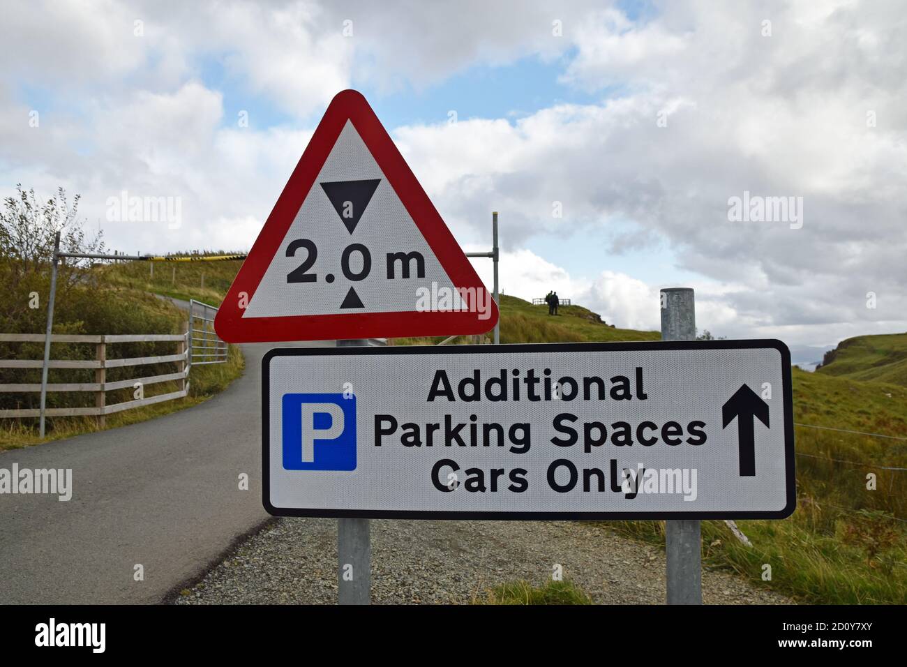 Two metre height restriction with blurred barrier in background. Sign for additional parking spaces cars only with arrow and parking icon. UK. Stock Photo