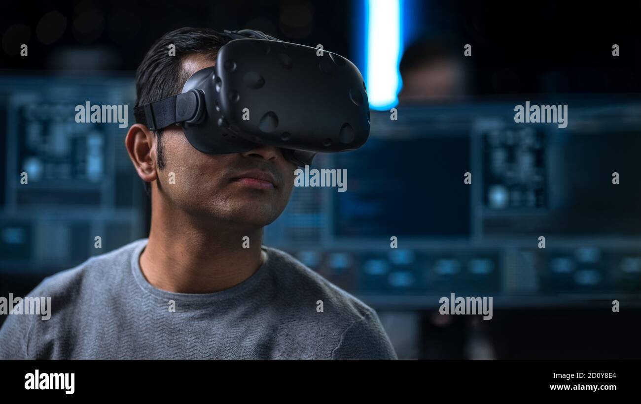Software Delevoper Wearing Virtual Reality Headset on His Head, Developing and Programming VR Game or Application. In the Background Technology Stock Photo