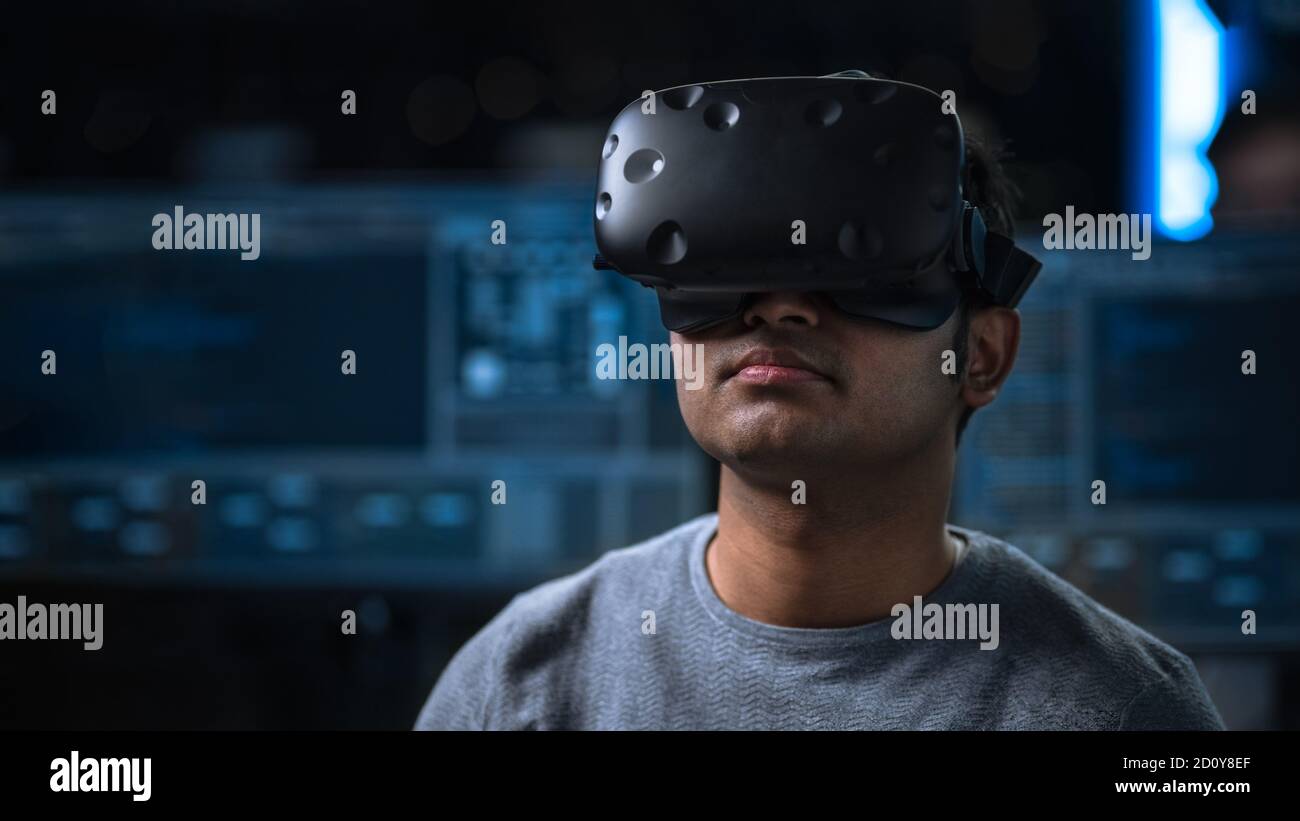 Software Delevoper Wearing Virtual Reality Headset on His Head, Developing and Programming VR Game or Application. In the Background Technology Stock Photo