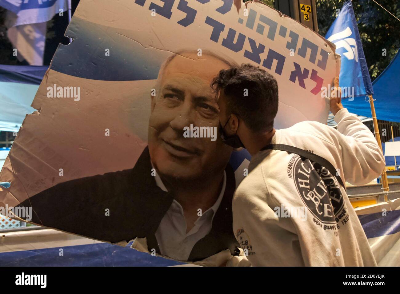JERUSALEM, ISRAEL - OCTOBER 03: A pro-Netanyahu counter-protester kissing a poster bearing the image of Netanyahu with a writing 'You will never walk alone' during a demonstration in front of prime minister's official residence despite a nationwide lockdown aimed at curbing the coronavirus pandemic on October 03, 2020 in Jerusalem, Israel. Israeli parliament approved last week a law restricting demonstrations as part of a coronavirus-related state of emergency, that critics say is aimed at silencing protests against Netanyahu over his indictment on corruption charges Stock Photo