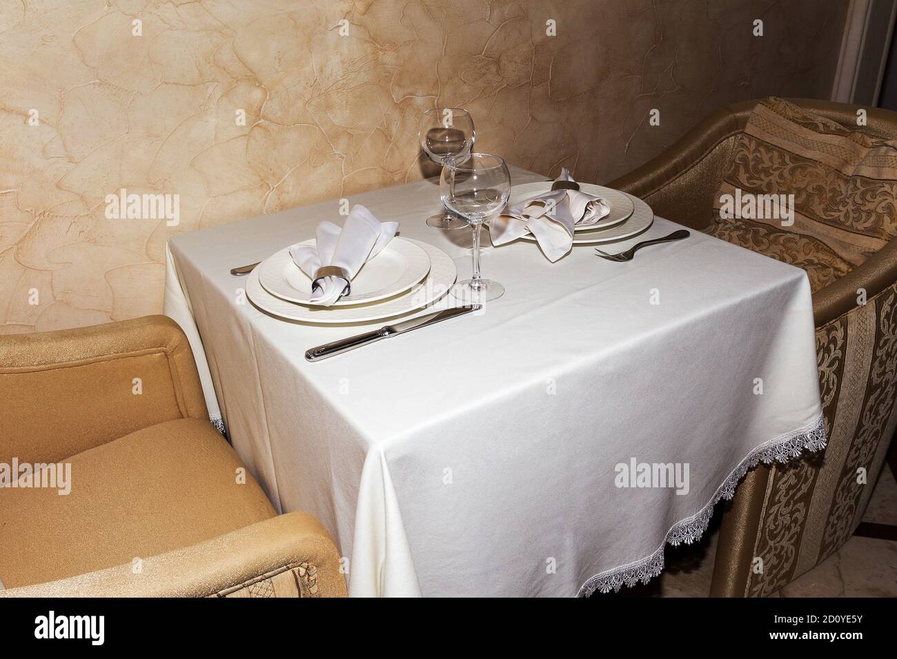 Elegant table setting with fork, knife and white napkin for two persons. A cozy cafe. Stock Photo