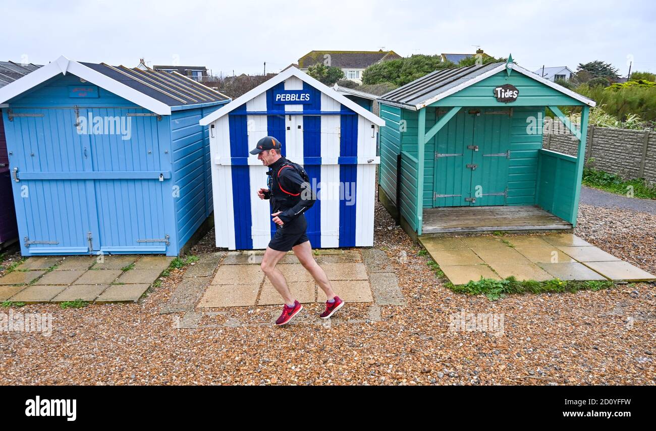 Worthing UK 4th October 2020 -  Runners in the Virtual London Marathon battle against the elements on a wet and windy day along Ferring seafront near Worthing as they reach their 20 mile mark : Credit Simon Dack / Alamy Live News Stock Photo