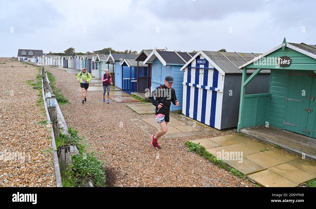 Worthing UK 4th October 2020 -  Runners in the Virtual London Marathon battle against the elements on a wet and windy day along Ferring seafront as they turn for home  back to Worthing as they pass their 20 mile mark : Credit Simon Dack / Alamy Live News . Stock Photo
