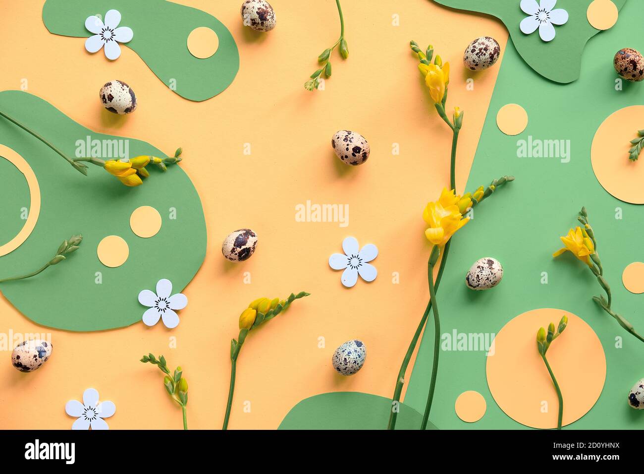 Easter background in green and yellow. Flat lay, top view with quail eggs, freesia flowers and paper circles.. Stock Photo