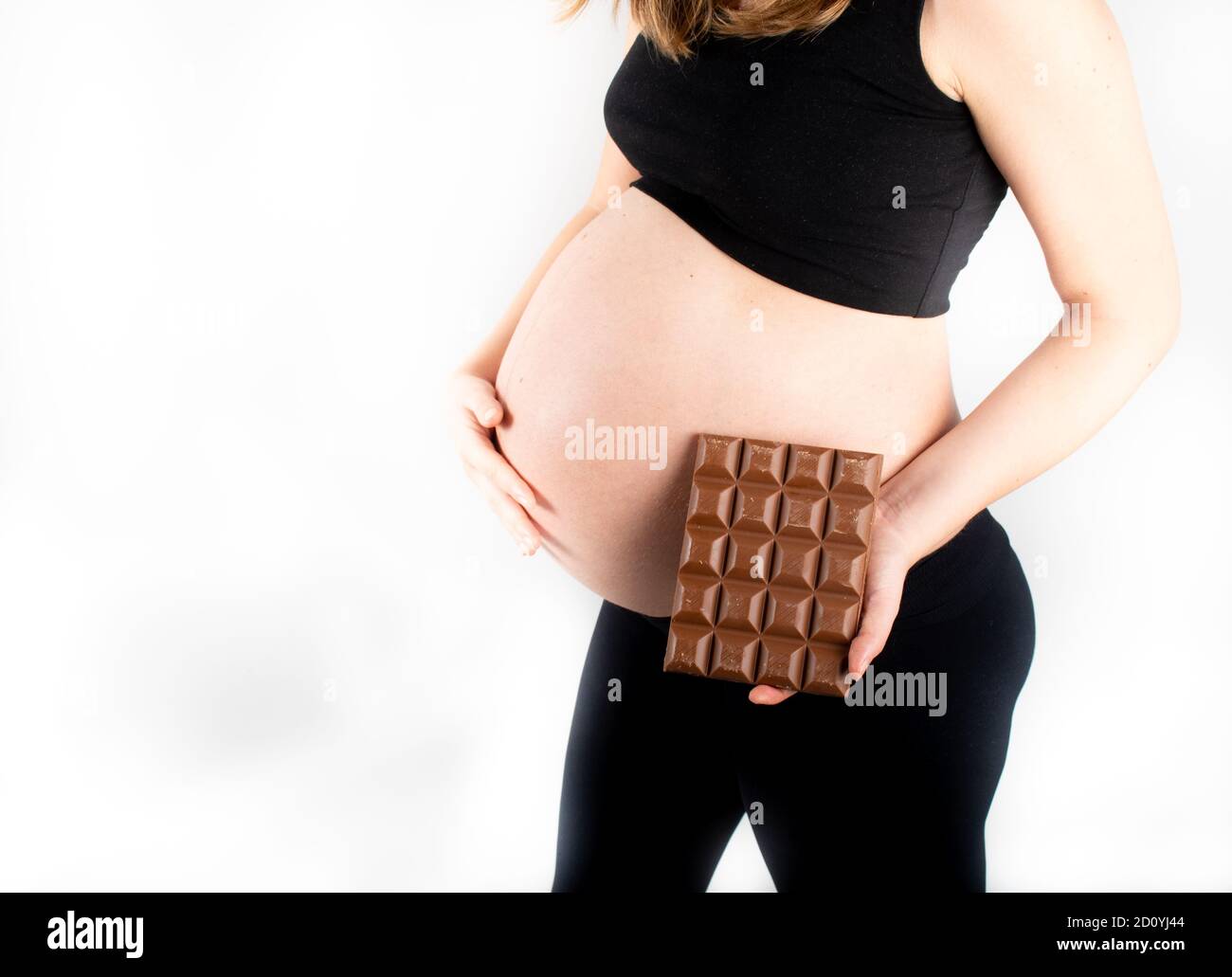 Pregnant woman holding a big dark chocolate bar. Gestational diabetes