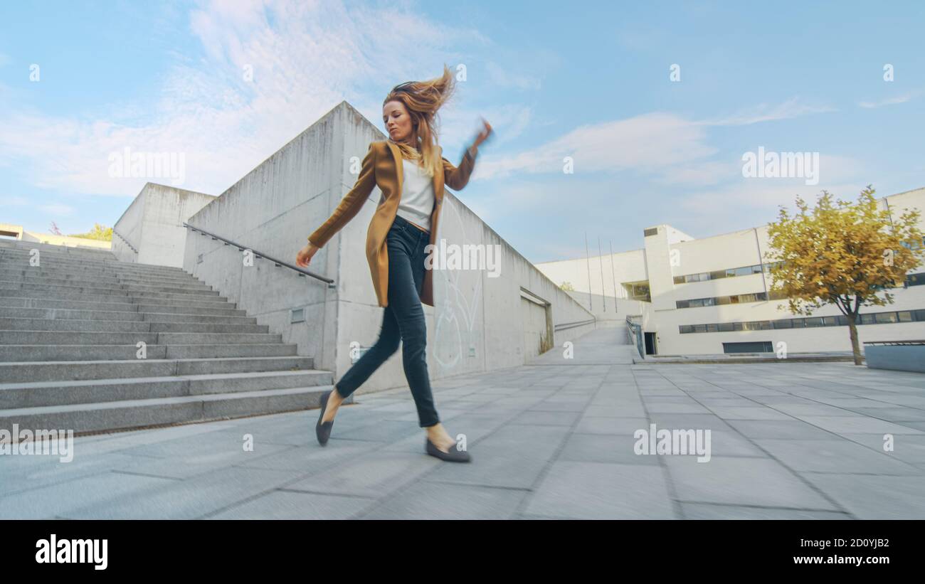 Cheerful and Happy Young Woman Actively Dancing While Walking Down the  Stairs. She's Wearing a Long Brown Coat. Scene Shot in an Urban Concrete  Park Stock Photo - Alamy