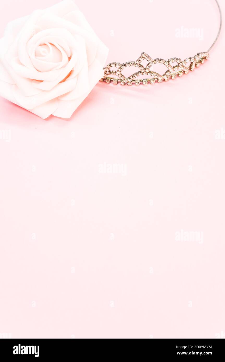 Vertical shot of an elegant crown next to a decorative rose on pastel pink  background Stock Photo - Alamy, image size:863x1390