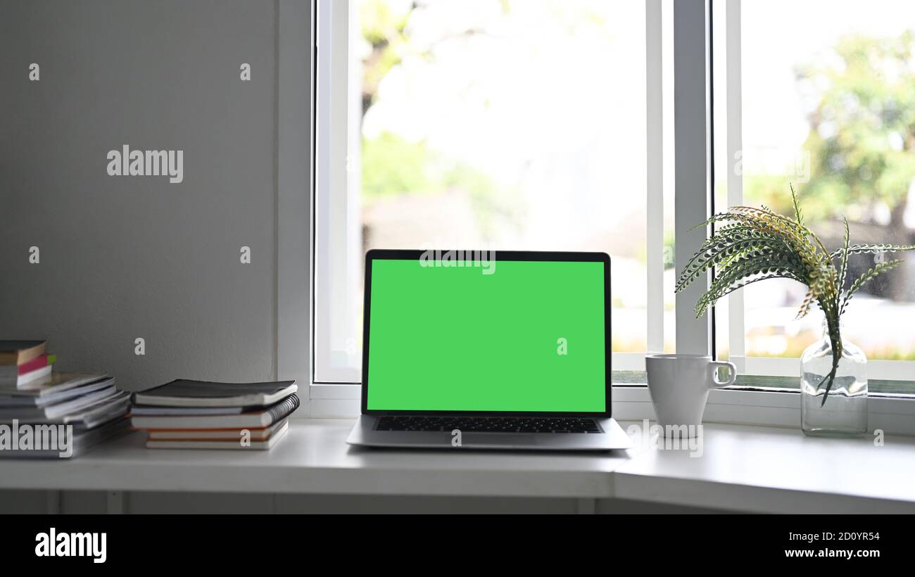 Workspace laptop computer with green screen and office supplies Stock