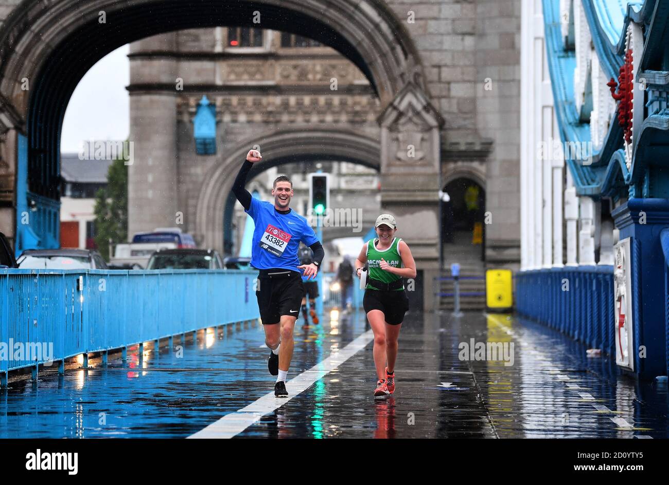 Runners wearing London Marathon running numbers cross Tower Bridge as