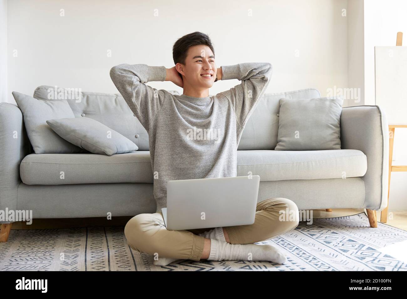 happy young asian business man staying at home sitting on carpet working using laptop computer happy and smiling Stock Photo