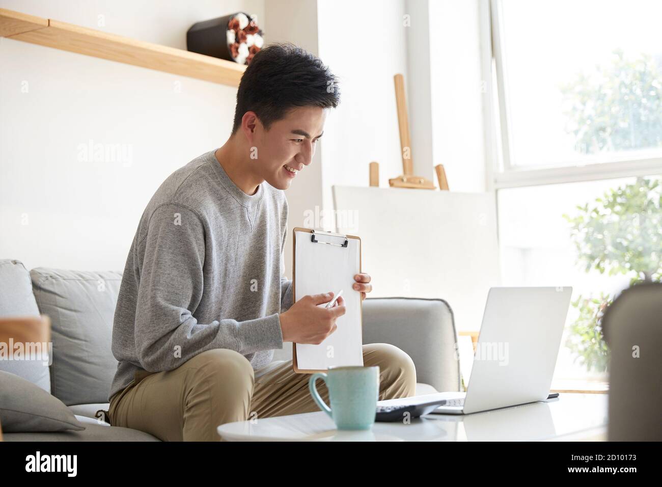happy and smiling young asian corporate executive working from home meeting with colleagues or clients using video call Stock Photo