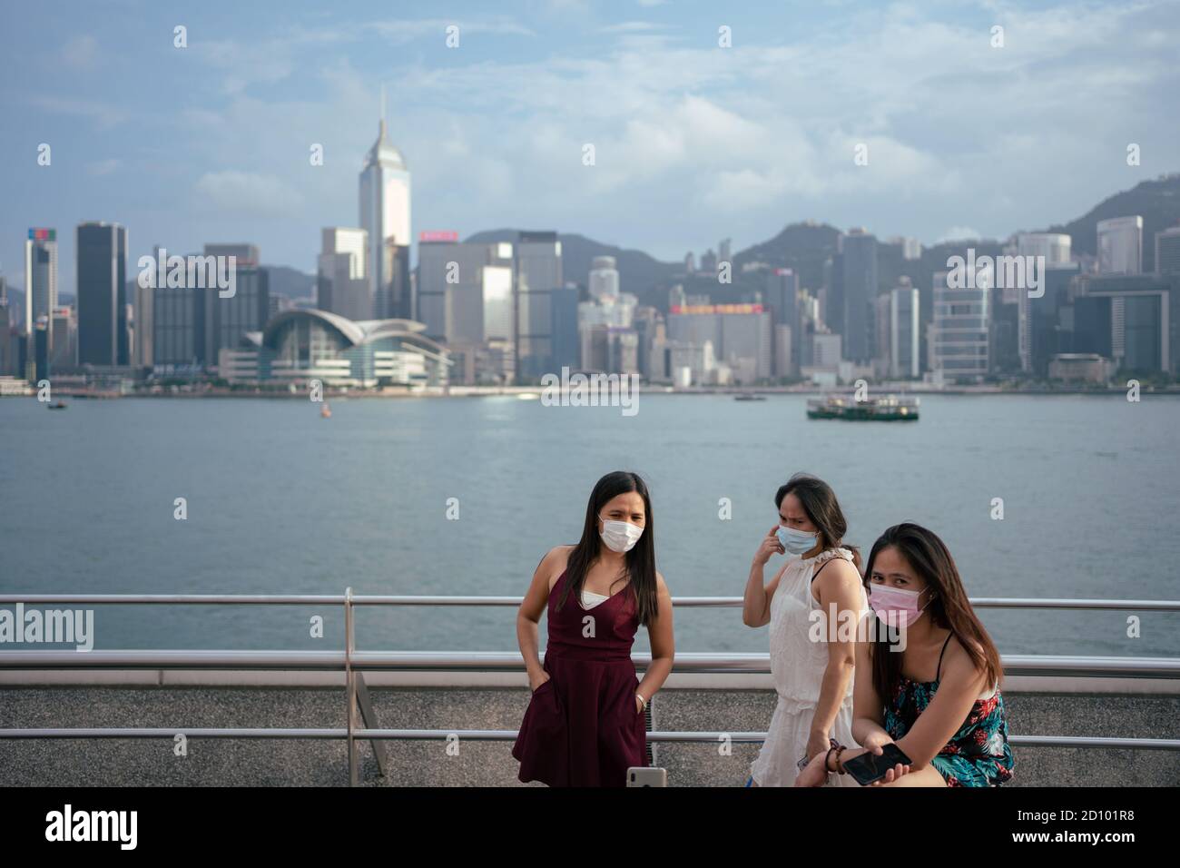 Three women taking pictures without their masks on. The current social distancing rules in Hong Kong only allow four persons to huddle as a group. Stock Photo