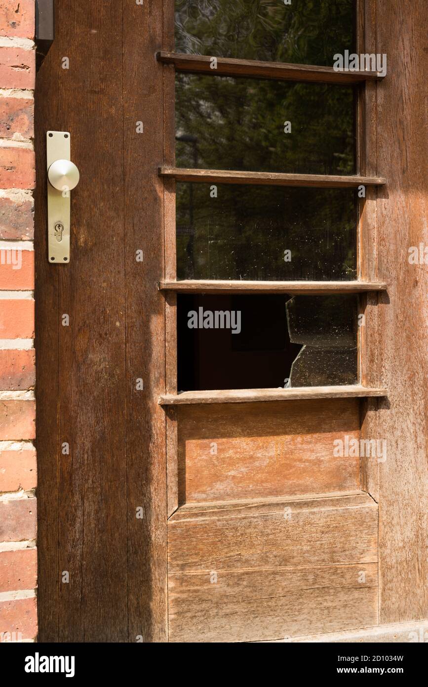Broken glass window in wooden door - crime, robbery, home invasion, abandoned Stock Photo