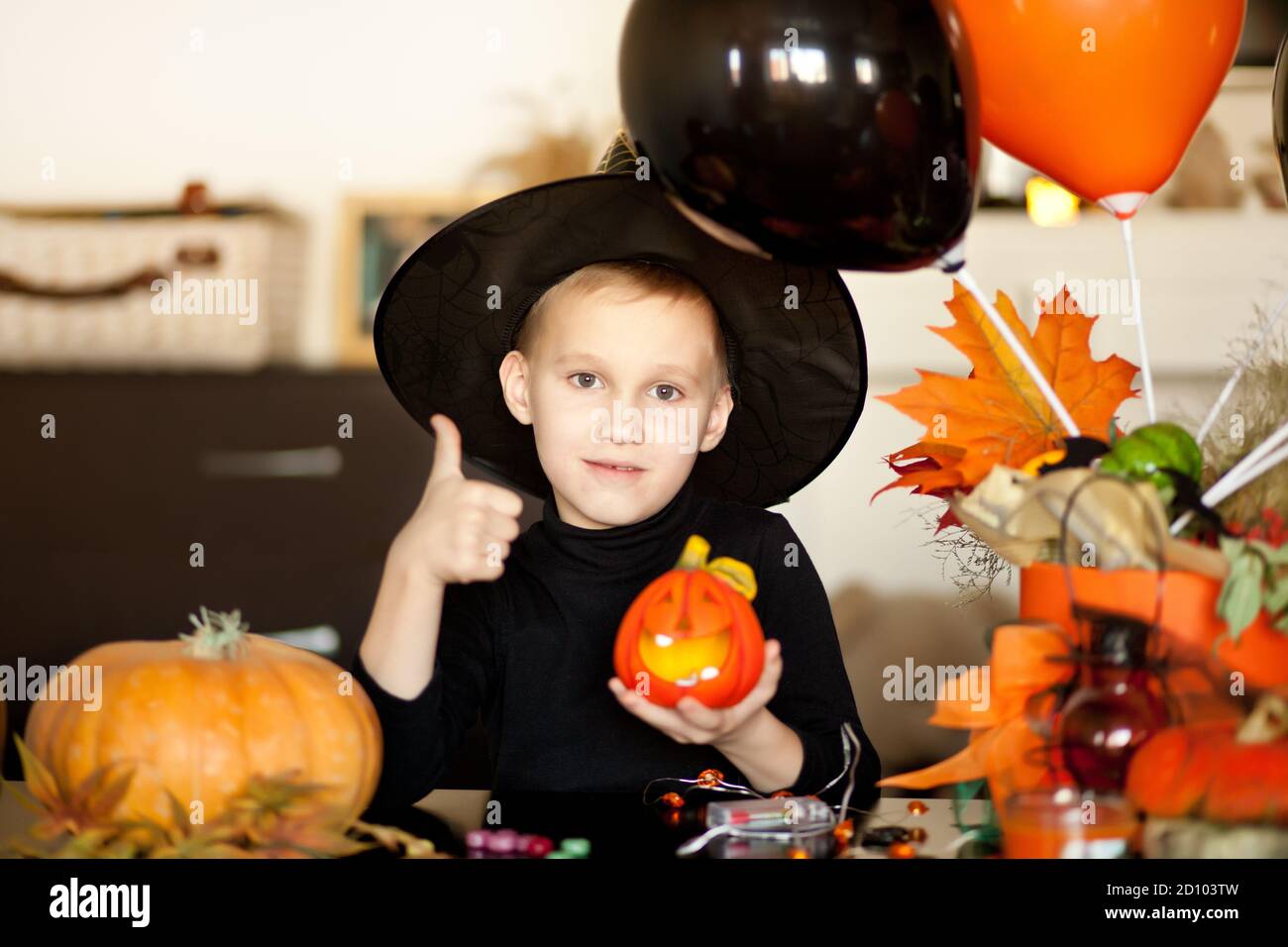 funny kid boy in witch costume for Halloween with pumpkin Jack in a hands. Stock Photo
