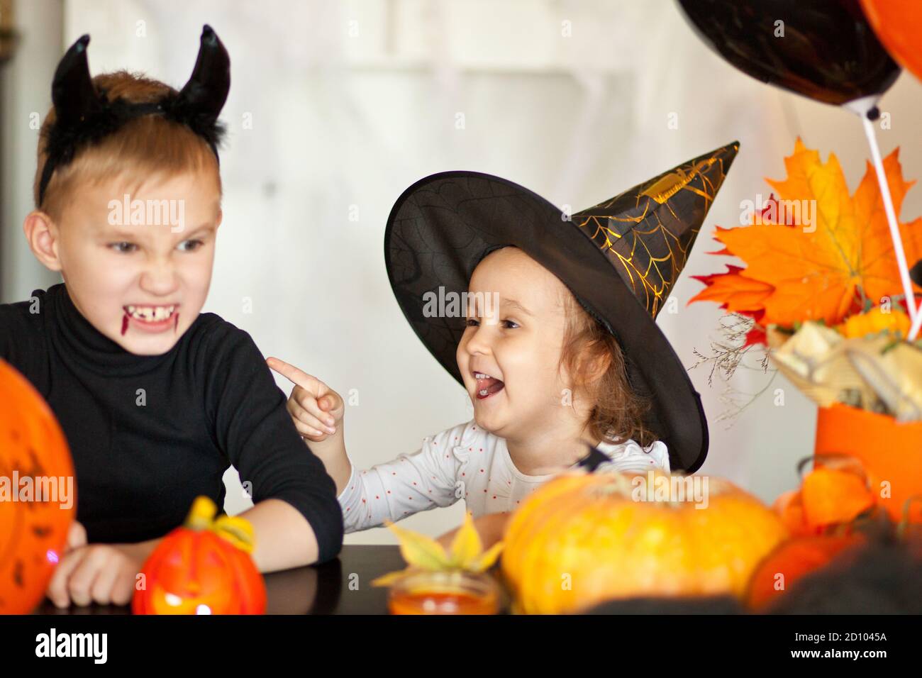 funny child girl and teen boy in witch and evil costumes for Halloween party Stock Photo