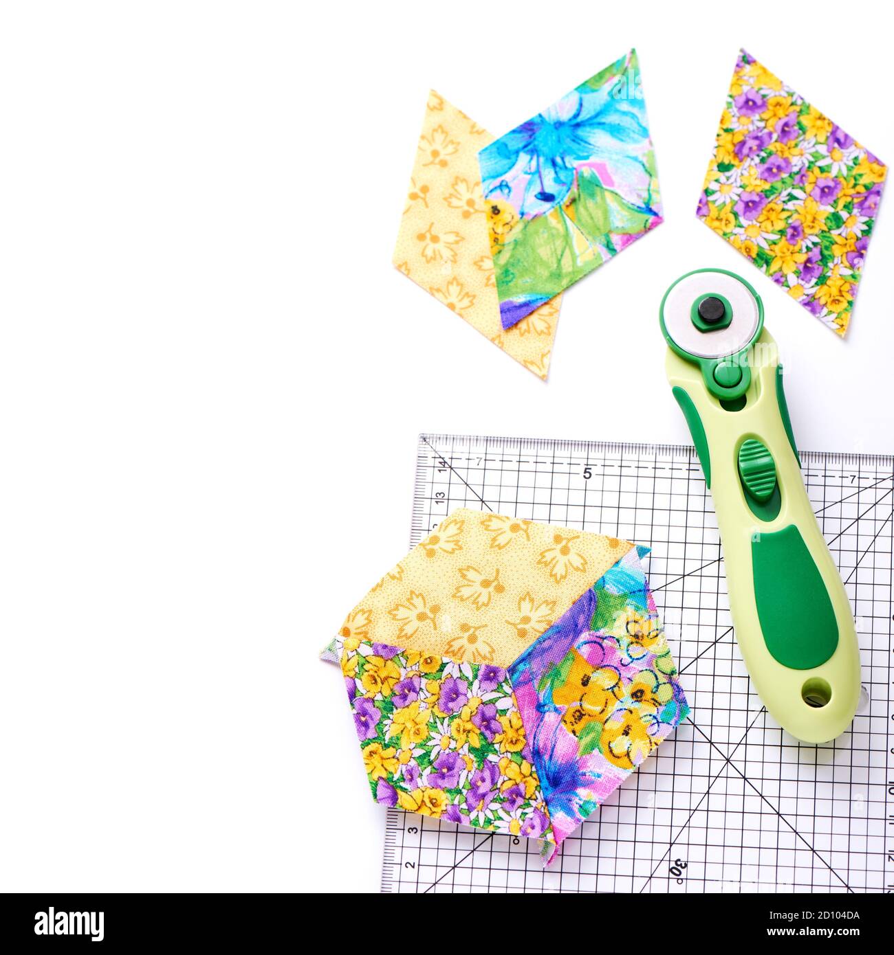 Pieces of quilt with rotary knife and ruler on white surface, top view ...