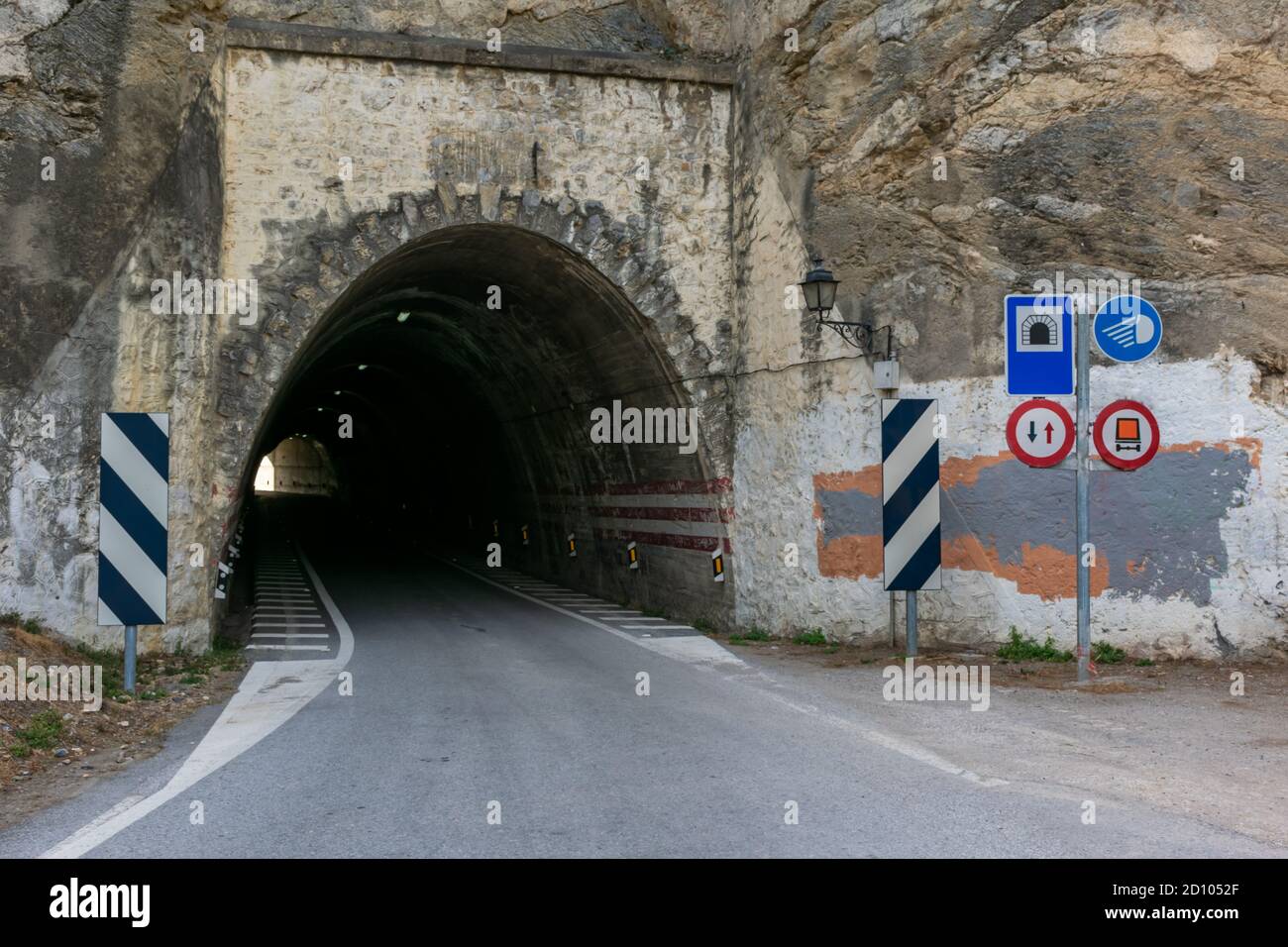 Old and narrow tunnel with several signs at the entrance, among other notices is the prohibition of circulating dangerous goods. Stock Photo