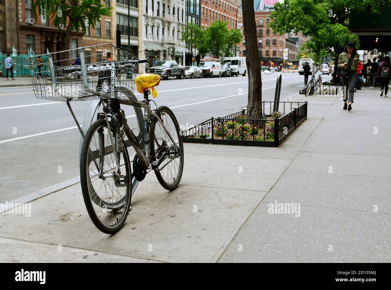 NEW YORK, USA - MAY 10, 2019: Bicycle chained to a stand on West 14th Street in downtown New York City on May 10, 2019. Pedestrians walk along the sid Stock Photo