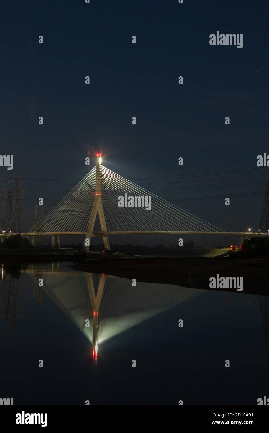 Cable-stayed concrete Flintshire Bridge,lit at night, spanning River Dee viewed from Connah's Quay. Fan like structure reflected in mirrored Estuary Stock Photo