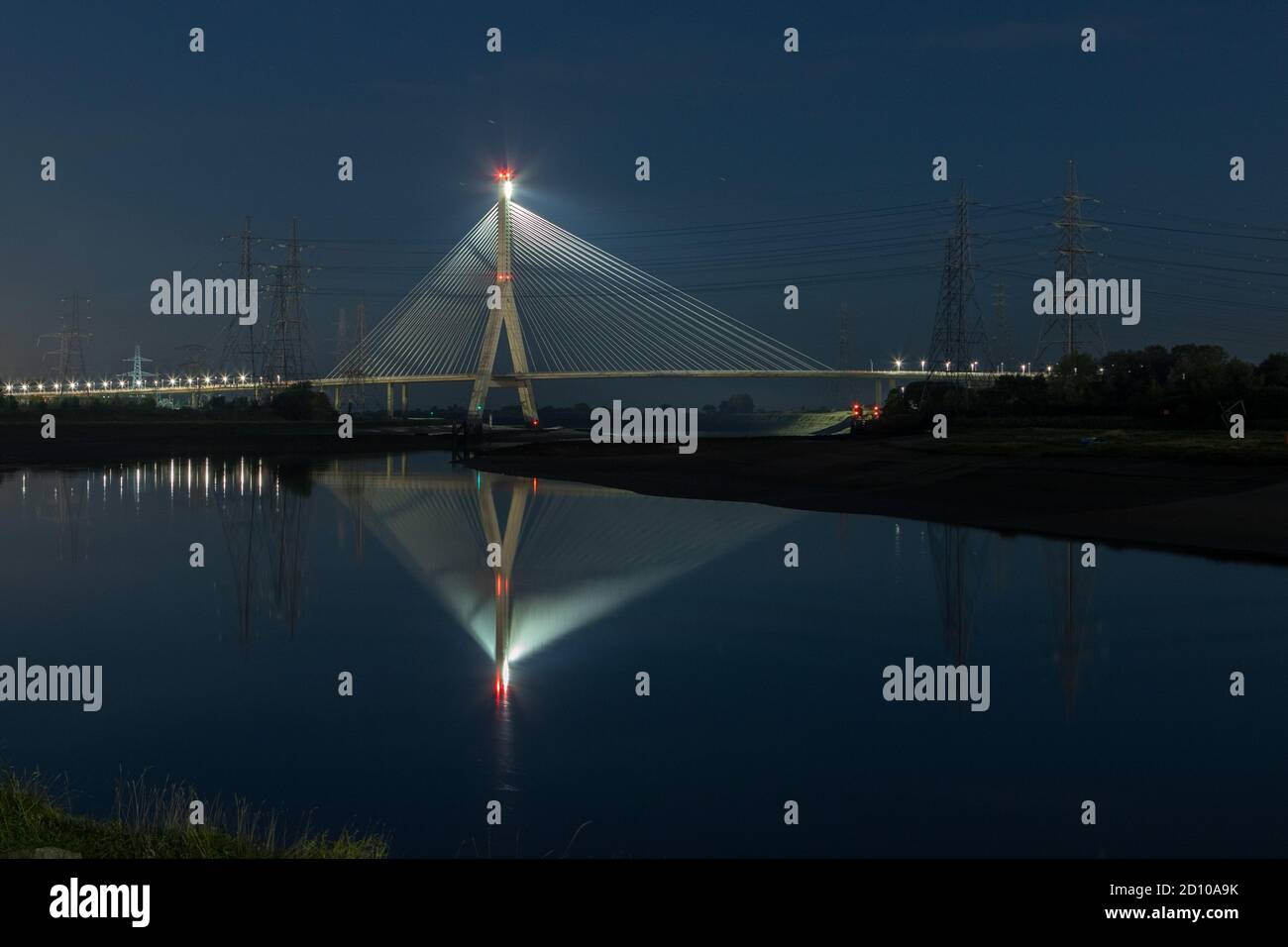 Cable-stayed concrete Flintshire Bridge,lit at night, spanning River Dee viewed from Connah's Quay. Fan like structure reflected in mirrored Estuary Stock Photo
