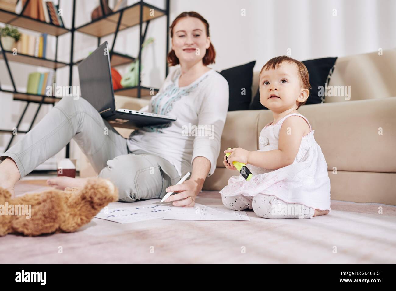 Mother looking at playing baby Stock Photo - Alamy