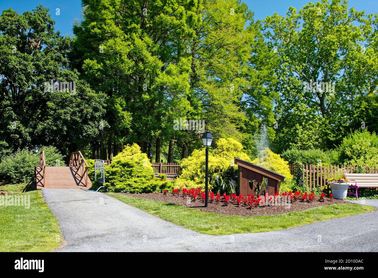 garden scene, trees, shrubs, flowers, small bridge, lamppost, bench, path, peaceful, Dutch Wonderland, Pennsylvania; Lancaster County; PA Stock Photo
