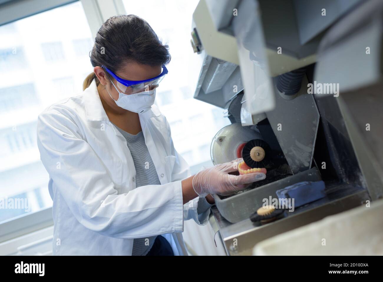 technician in dental lab working on an implant with grinder Stock Photo