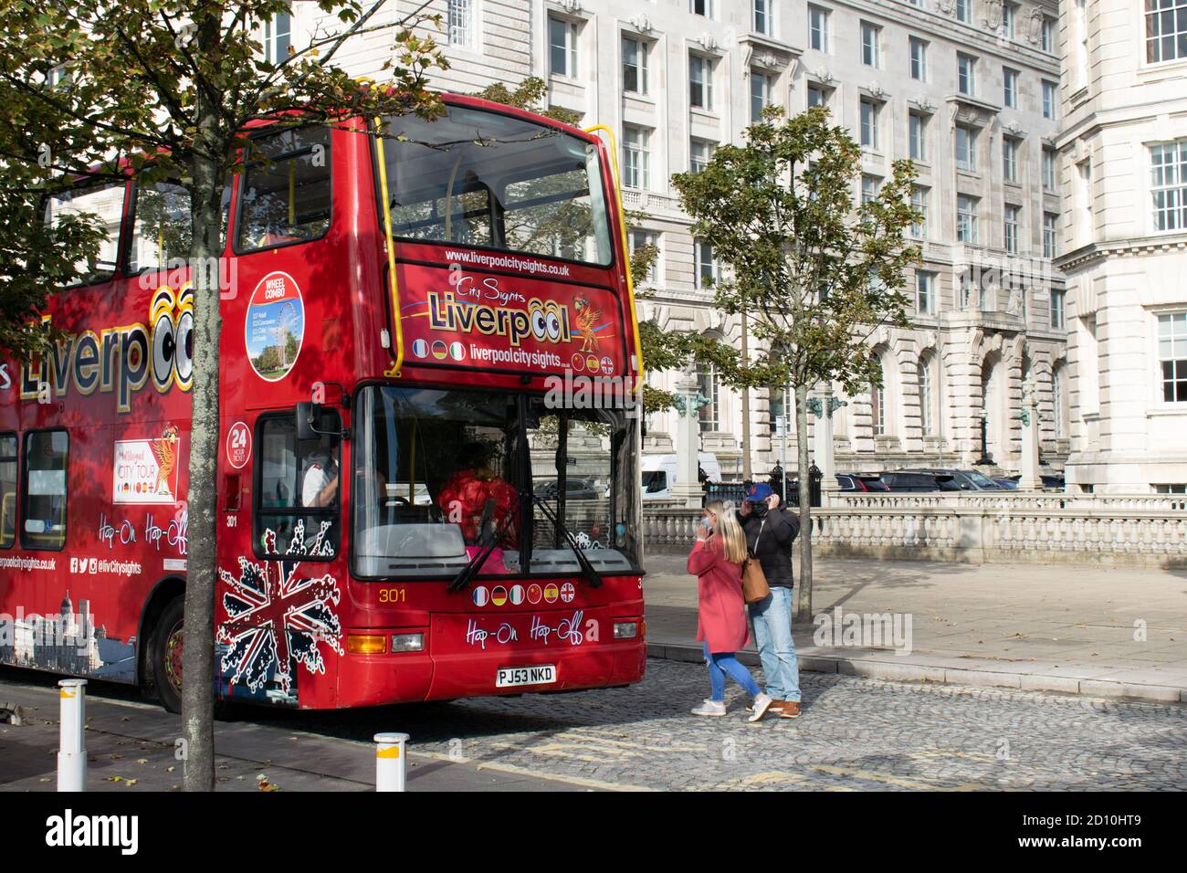 Hop on Hop off city sights tour bus Liverpool with passengers alighting in front of Liver building Stock Photo