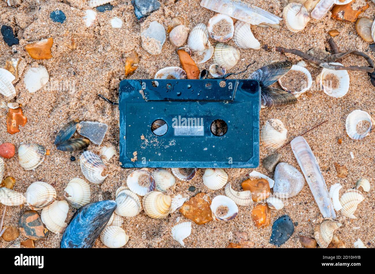 An old plastic cassette tape washed up on the high water tideline on the shore of The Wash, Norfolk. Stock Photo