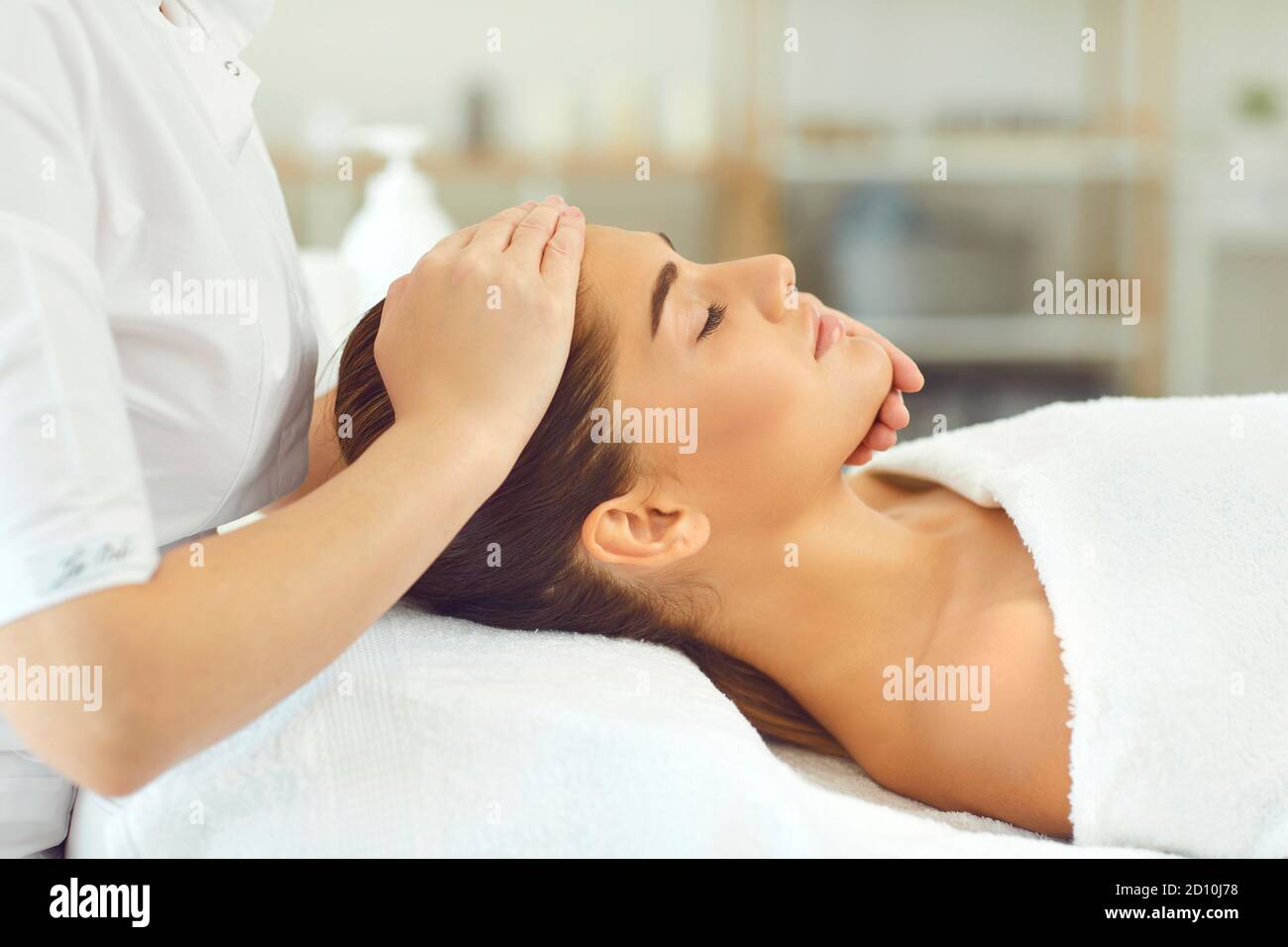 Cosmetologist making manual rejuvenating facial massage for young woman in beauty salon Stock Photo