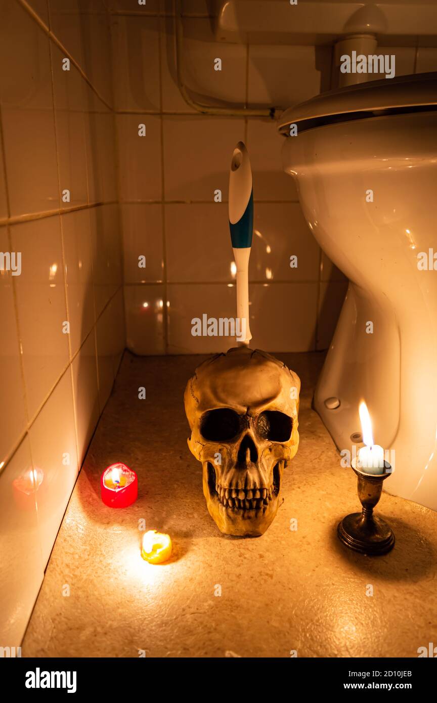 Halloween restroom scene with skull toilet brush holder and candles Stock Photo