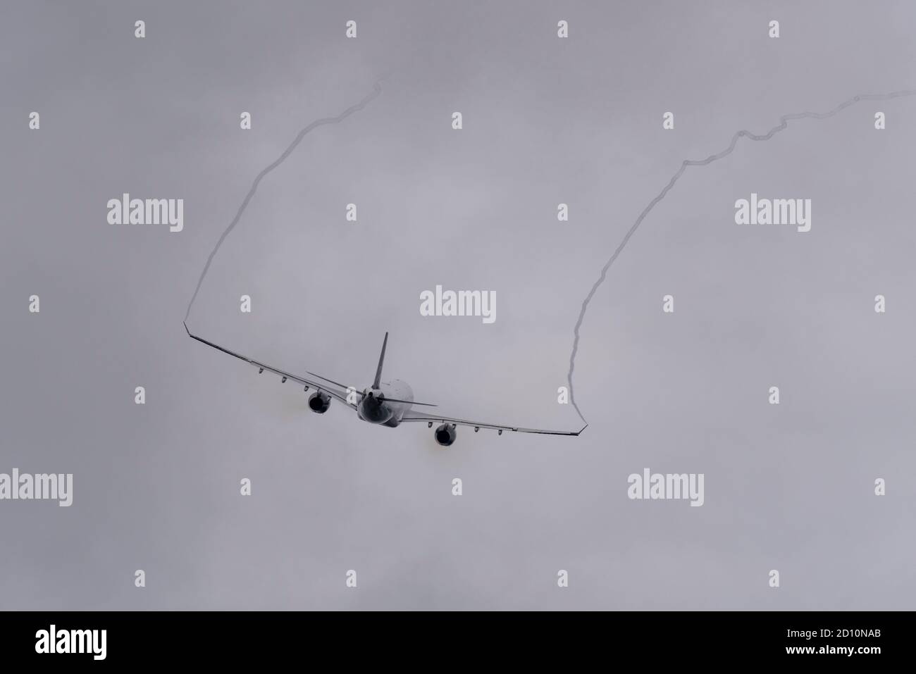 Jet airliner plane taking off in bad weather from London Heathrow Airport, UK, climbing into heavy clouds leaving streamers of vortices Stock Photo