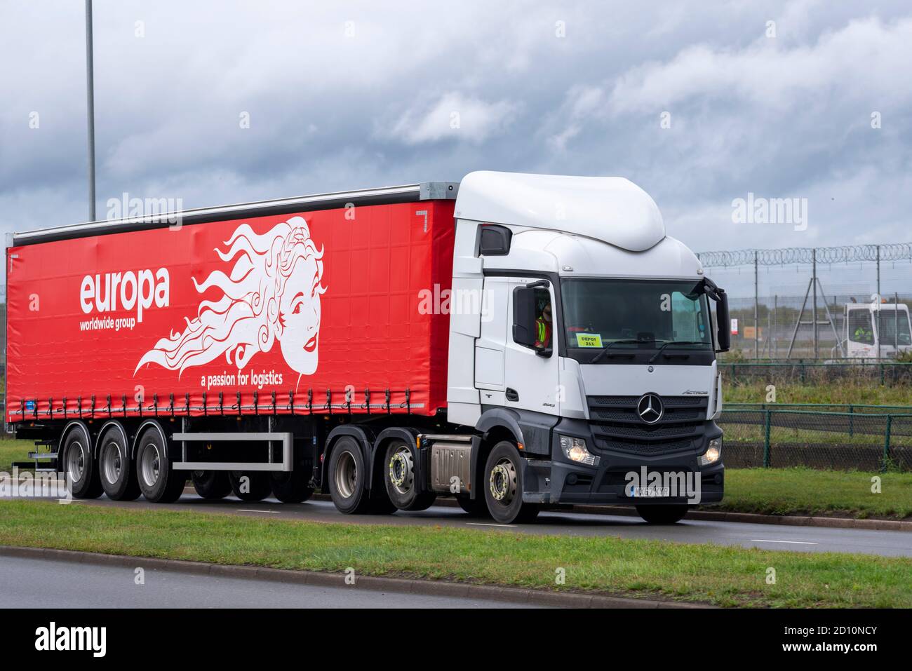 Europa worldwide group, transport, logistics, lorry passing London Heathrow Airport, UK. Mercedes articulated curtain sider, tautliner vehicle Stock Photo