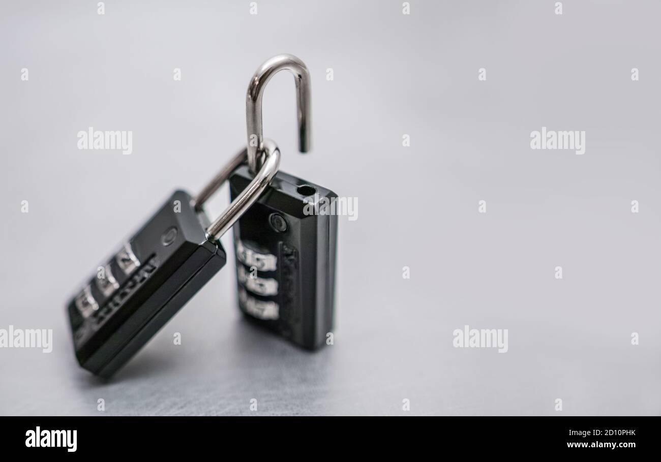 Two padlocks, one is open, the other remains closed and hooked.. Stock Photo