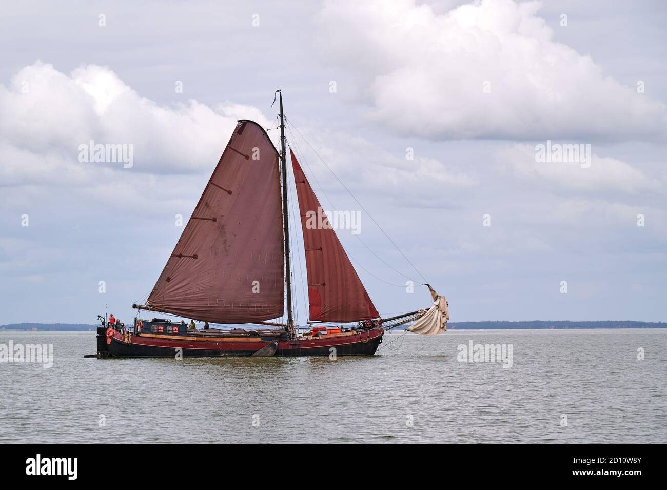 Flat bottom ship with red sails on the IJsselmeer Stock Photo