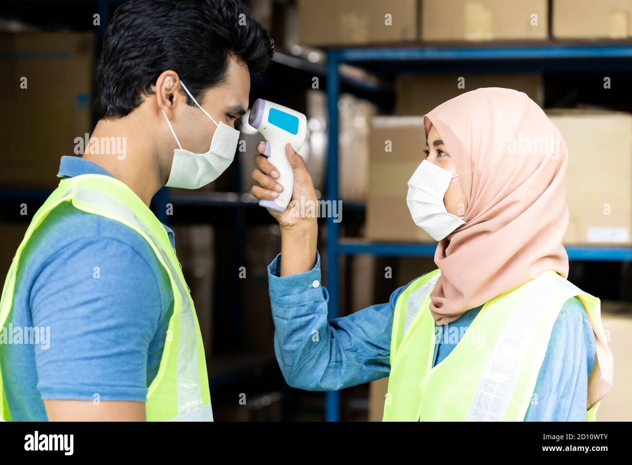 Islam asian warehouse worker taking temperature to worker before getting in factory after reopening from city lockdown from COVID-19 coronavirus pande Stock Photo