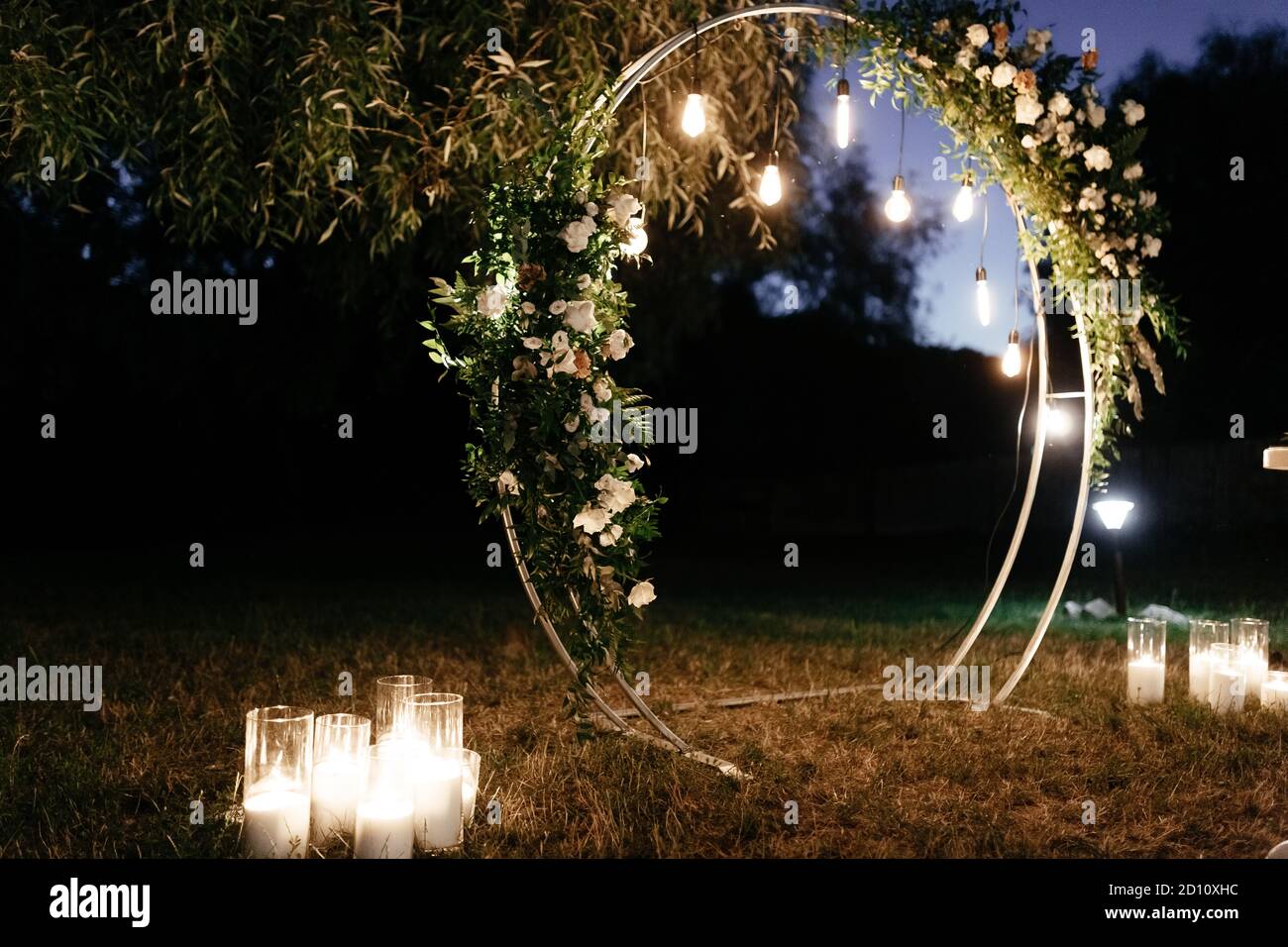Circle wedding arch decorated with white flowers and lights in the